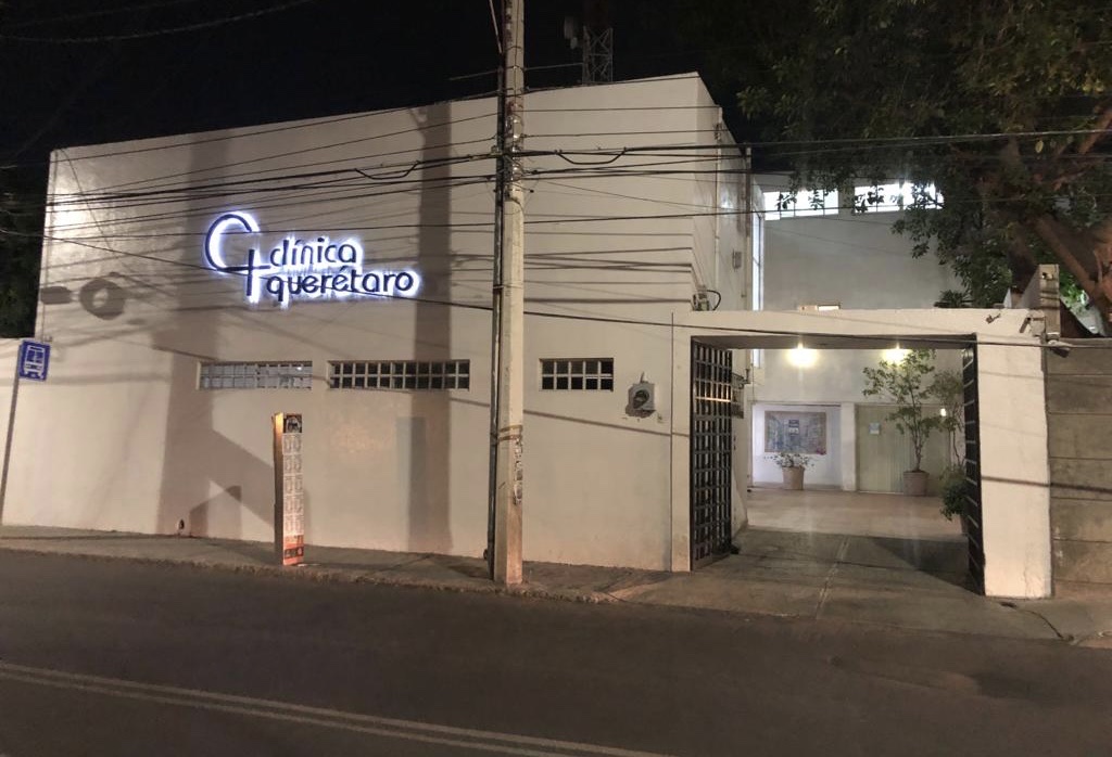 Fachada iluminada de Clínica Querétaro por la noche, sobre Av. 20 de Noviembre